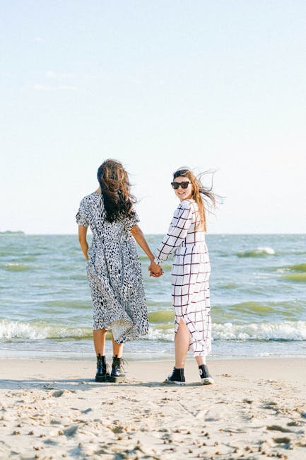 Romantic moment of a couple holding hands at the beach, enjoying the sun and waves.